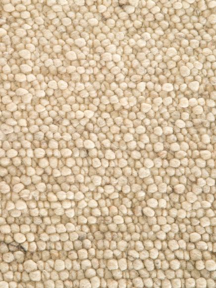 Teppich zeigt enge Anordnung von beige bis hellbraunen, dicken, gewellten Knötchen im Nahaufnahme.
