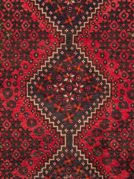 Orientteppich zeigt rote und schwarze geometrische Muster in einem wiederholenden Design.