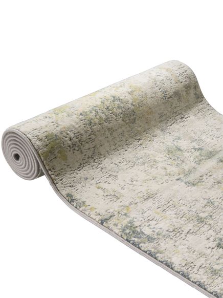Teppich liegt halb aufgerollt, zeigt abstraktes Muster in Creme, Grau und Grün auf hellem Hintergrund.
