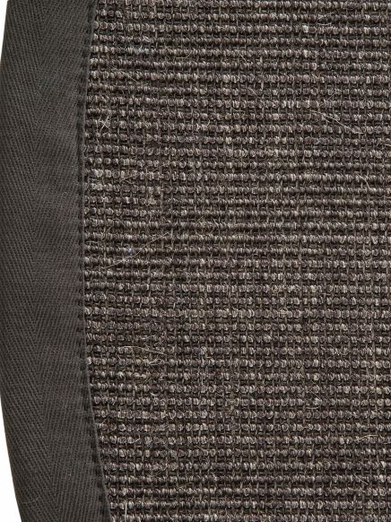 Türkis-braune gewebte Matte mit schwarzem Stoffrand auf hellem Hintergrund.