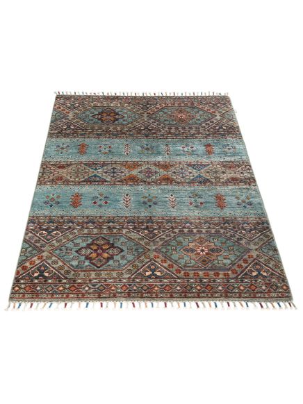Teppich liegt flach mit geometrischem Muster in Blau, Braun und Rot auf hellem Hintergrund.