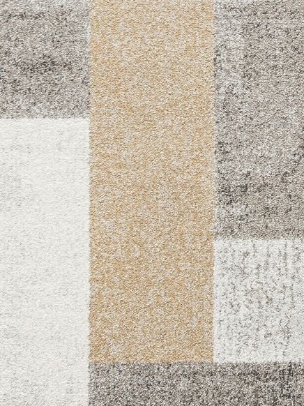 Teppich zeigt rechteckige Farbflächen in Beige, Weiß und Grau in einem Muster.