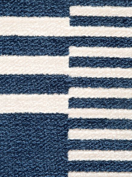 Teppich zeigt blau-weiße horizontale Streifen in unterschiedlicher Breite und unregelmäßigem Muster.