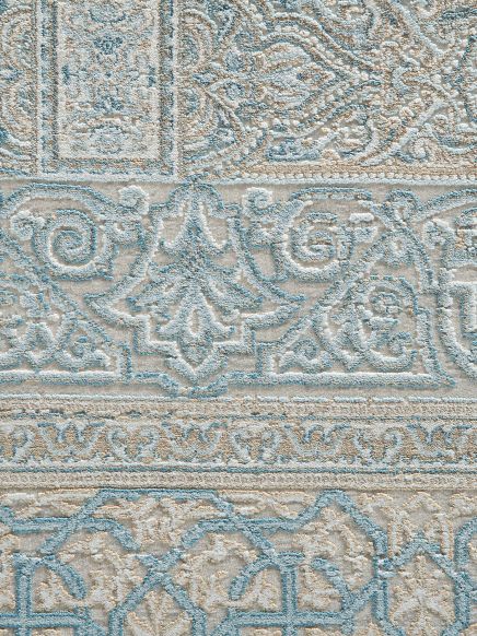 Teppich zeigt geometrische und florale Muster in Beige und Blau auf hellem Hintergrund.