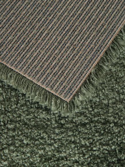 Ein Teppich liegt auf einem anderen Teppich, der untere hat einen dichten Flor, der obere eine gewebte Struktur.