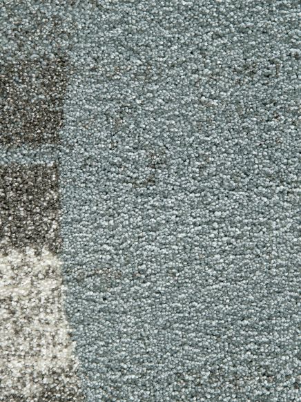 Detailaufnahme eines Teppichs mit gemusterten Bereichen in Grau- und Blautönen.