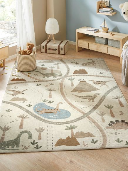 Kinderteppich liegt auf Holzboden in Zimmer mit Spielzeug, Lampe und Kommode.