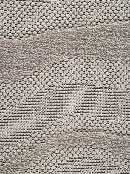 Teppich zeigt verschiedene Texturen und Muster in wellenförmigen Linien in neutralen Grautönen.