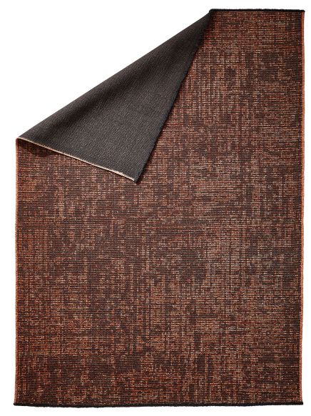 Teppich liegt flach, Ecke ist hochgeklappt, braun gemustert, Rückseite dunkelgrau.