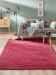 Roter Teppich liegt vor grauem Sofa mit Kissen und Decke im modernen Wohnzimmer.