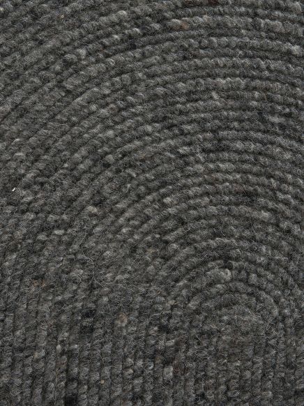Dunkelgrauer Wollteppich zeigt spiralförmige Struktur in Nahaufnahme.