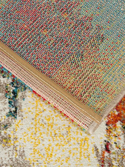 Teppich zeigt bunte Muster, Ecke umgeklappt und Rückseite mit Webmuster sichtbar.