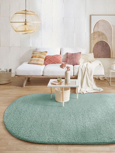 Gartenmöbel Couch mit Kissen, Couchtisch mit Deko auf Teppich in modernem Wohnzimmer.