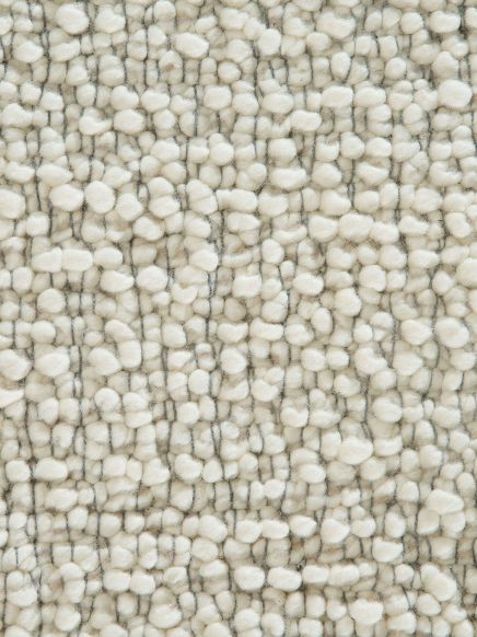 Nahaufnahme von weiß-grauem Wollteppich mit unregelmäßiger, strukturierter Oberfläche