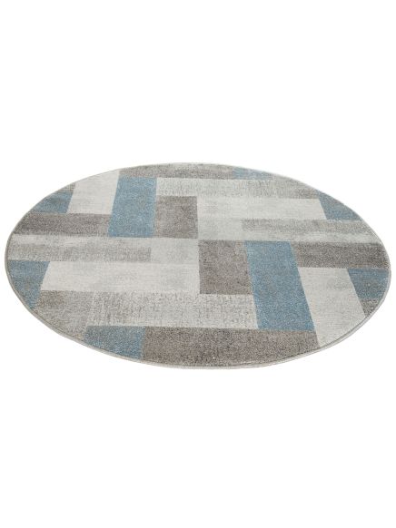Runder Teppich mit geometrischem Muster aus blauen, grauen und weißen Rechtecken auf weißem Hintergrund.