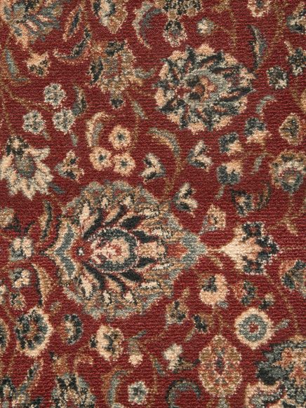Roter Teppich zeigt florales Muster mit beigen und schwarzen Details, dichter Stoffstruktur.