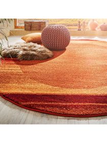 Runder teppich legt auf hellem holzboden, dekoriert mit kissen, fell und gestricktem pouf.