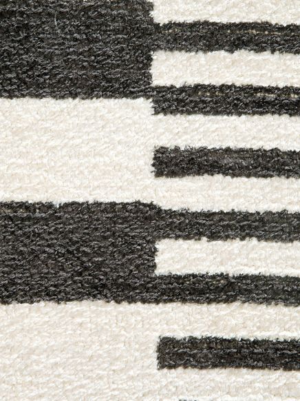 Teppich zeigt schwarz-weiße geometrische Streifenmuster in einem Innenraum.