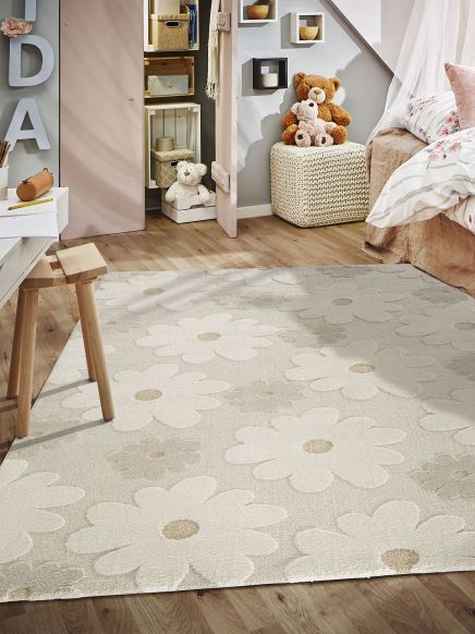Teppich liegt auf Holzboden, Kuscheltiere sitzen auf Hocker, daneben Bett und offener Schrank.