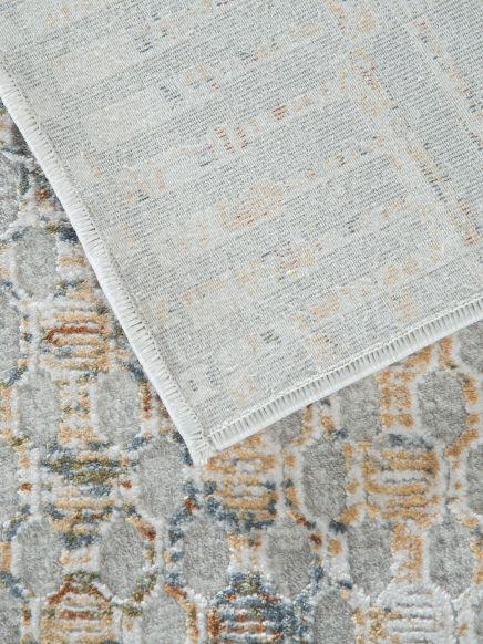 Zwei Teppiche, einer liegt umgeklappt auf einem gemusterten Teppich mit geometrischem Design.