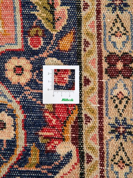 Messkarte liegt auf gemustertem Teppich mit Ornamenten in Blau, Rot, Beige und Gelb.