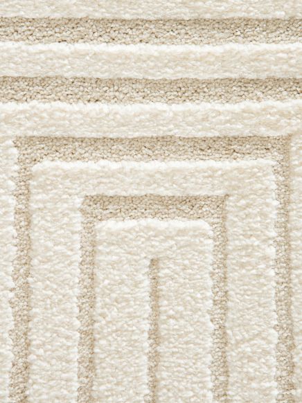 Teppich zeigt geometrisches Muster mit rechteckigen Streifen in Beige und Weiß.