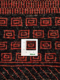 Messkarte liegt auf textilem Gewebe mit roten und schwarzen geometrischen Mustern.