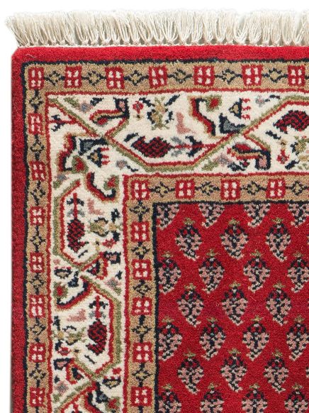 Teppich zeigt rote, beige und weiße Muster mit Fransen am oberen Rand, Detailaufnahme Ecke.
