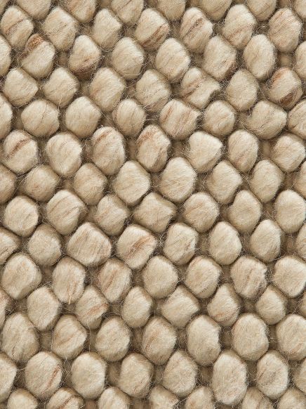 Dicke, beige Fasern formen enge, noppige Strukturen auf einem Teppichboden.