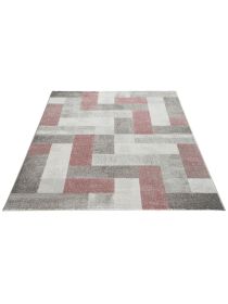 Teppich zeigt geometrisches Muster aus rosa, grau und weißen Rechtecken auf hellem Grund.