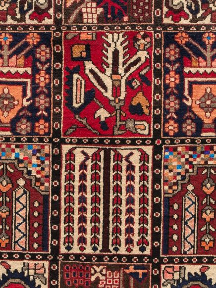 Teppich zeigt geometrische Muster und florale Motive in Rot, Blau und Beige.