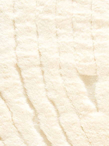 Flauschiger weißer Teppich mit unregelmäßigen Streifen in hellem Raum.