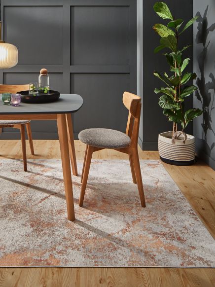 Stuhl steht neben Tisch mit Karaffe und Gläsern, Zimmer mit Pflanze und Teppichboden.