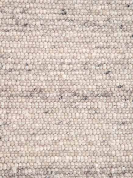 Nahaufnahme von beige-grauem Teppich mit grober gewebter Struktur und unregelmäßigen dunklen Punkten.