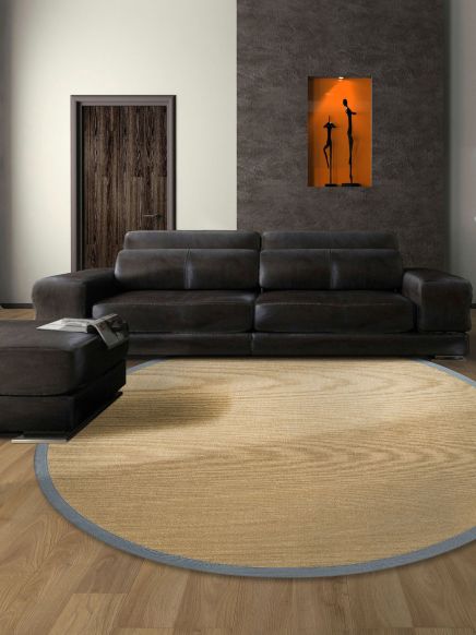 Dunkles Sofa steht vor grauer Wand mit eingelassener Nische mit zwei Skulpturen, rund beiger Teppich.
