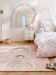 Kinderzimmer mit Regenbogen-Wandbild und Teppich ein Bett mit Einhorn-Kissen und Kronenmuster-Bettwäsche