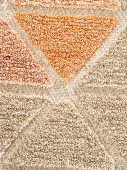 Wollstoff zeigt orange und beige dreieckige Muster auf hellbeigem gewebtem Hintergrund.