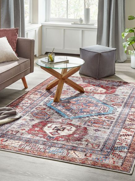 Teppich mit orientalischem Muster liegt in einem modernen Wohnzimmer neben Glastisch und Sofa