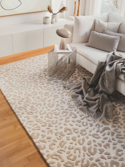 Sofa mit Kissen bedeckt mit Decke neben Beistelltisch und Teppich mit Muster in Wohnzimmer.