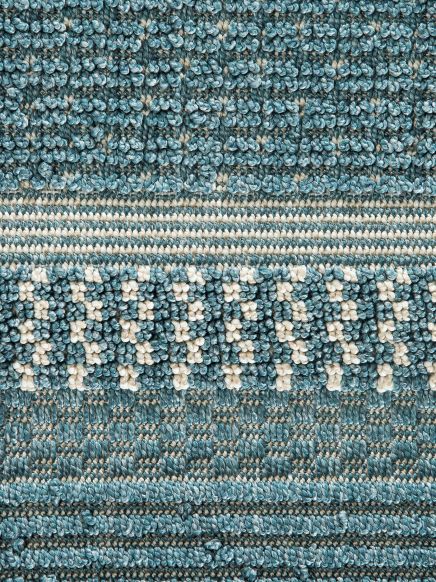 Nahaufnahme eines gemusterten blauen und weißen Teppichs mit detailreicher Textur in symmetrischem Design