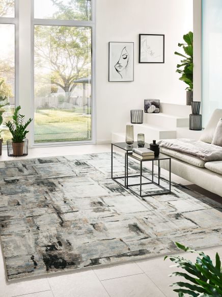 Teppich im abstrakten Design liegt im modernen Wohnzimmer mit großen Fenstern und Pflanzen